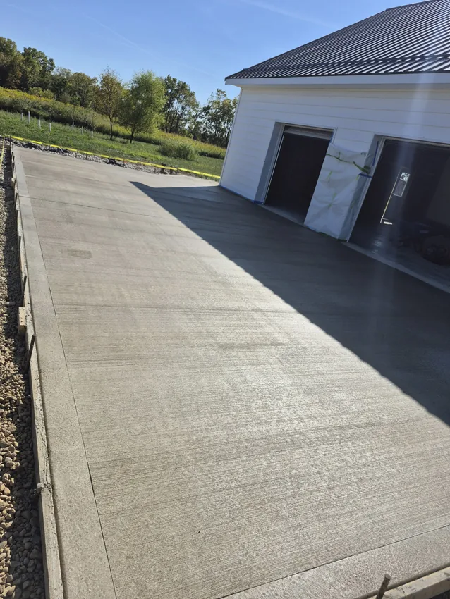 Finished concrete driveway leading to a detached residential garage